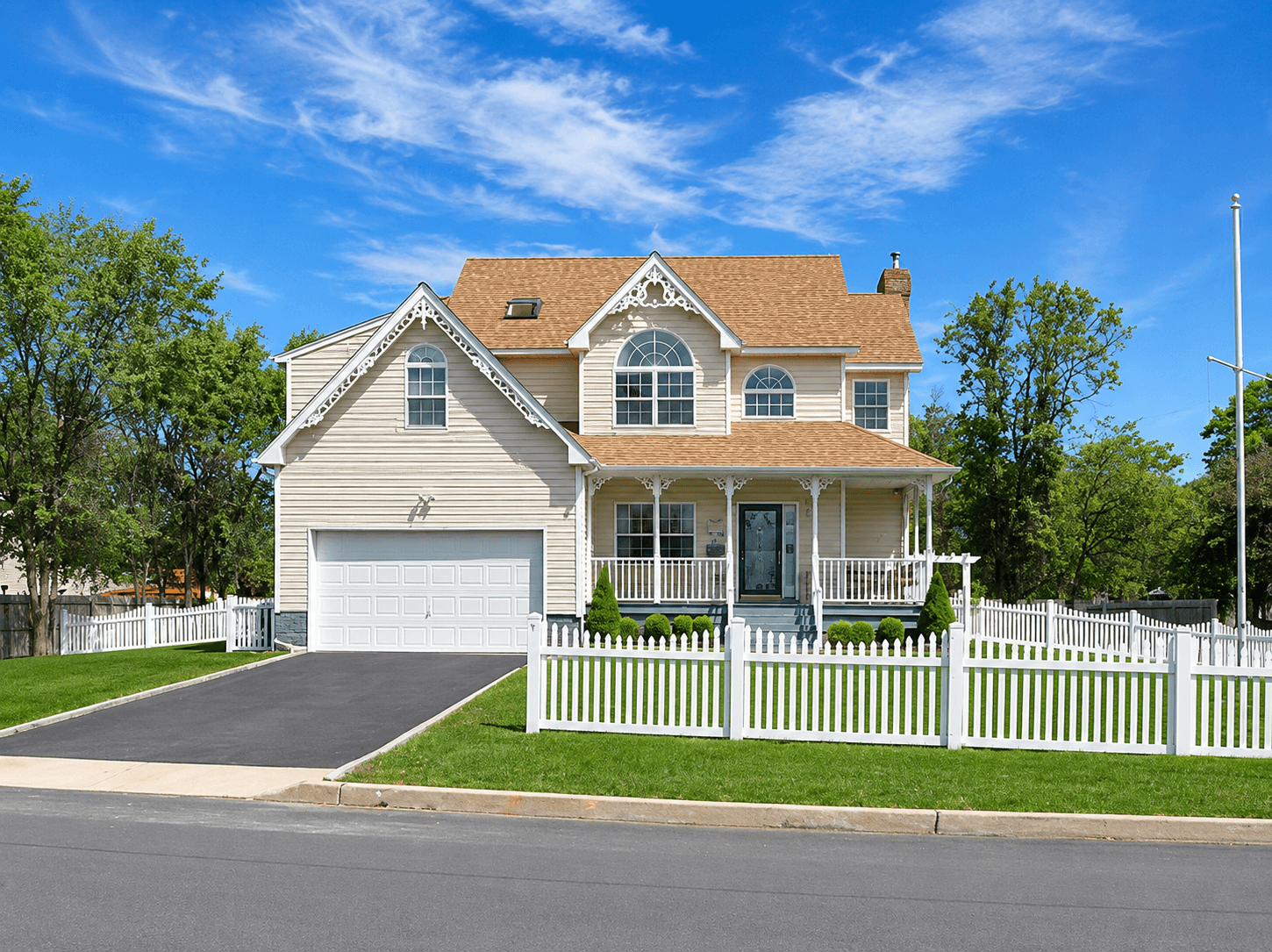 White suburban home with driveway, fence, windows, gutters, and patio areas
